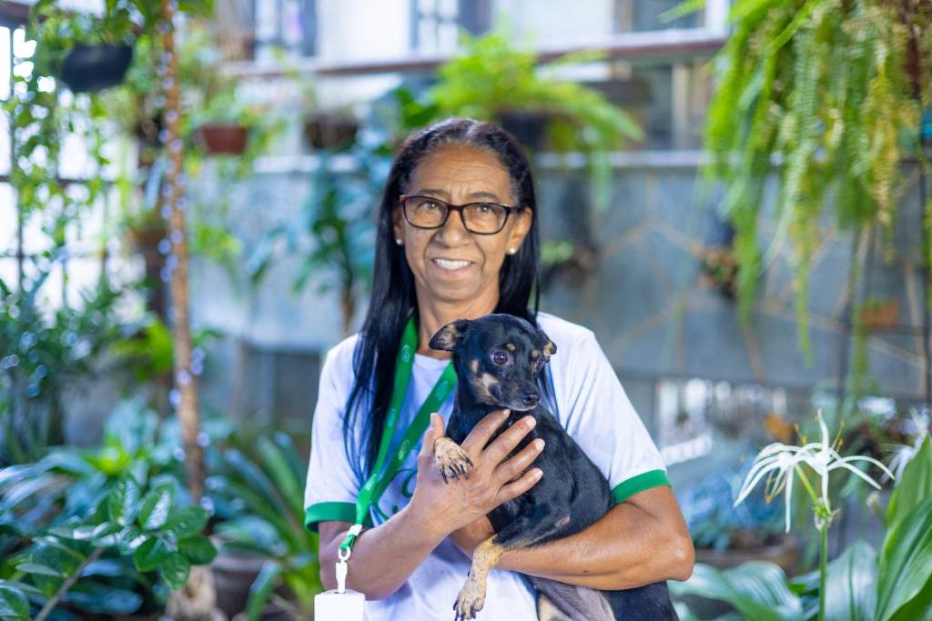 Funcionária do Pet Hotel Pampulha carregando um cachorro com cuidado e carinho